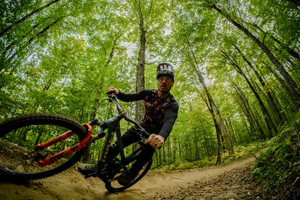 Author, Brice Shirbach, rides a berm through the VT forest, shot through a wide angle lens.