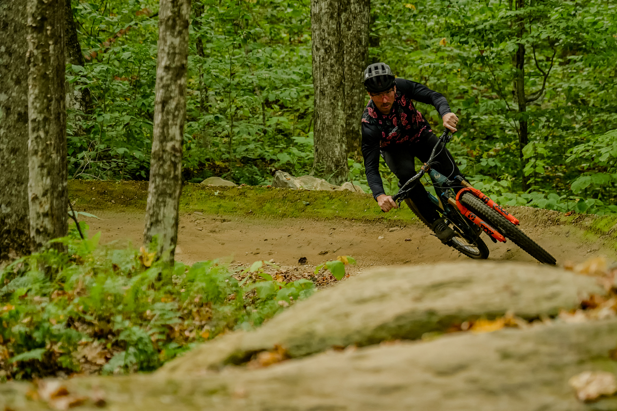 Author, Brice Shirbach, rides trail in a forest in Killington.