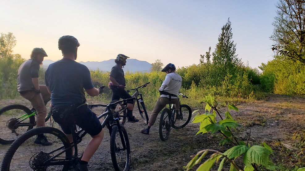 Five mountain bikers pause while riding in Maine during sunset