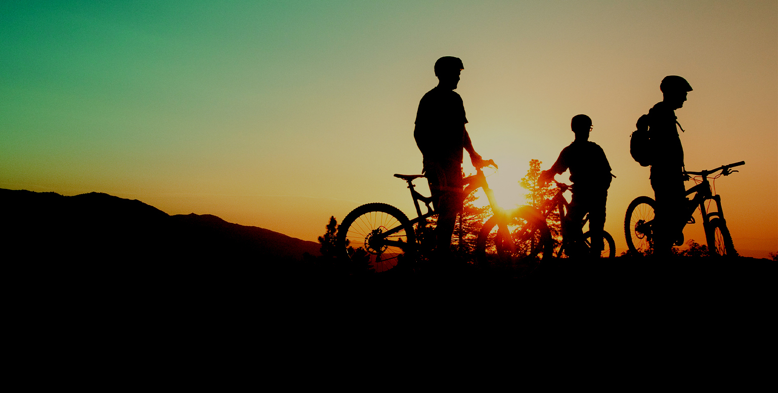 a group of three riders' silhouettes with sunset in the background