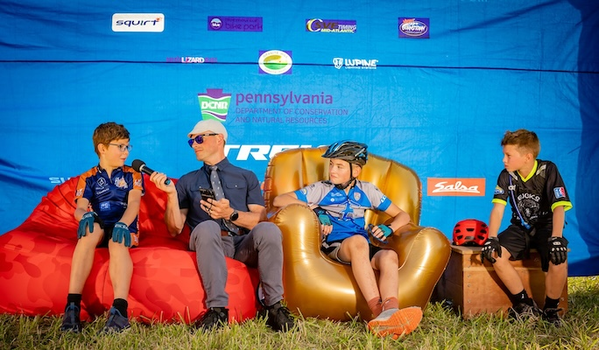 NICA riders from Pennsylvania on inflatable couch, speaking into microphone. 
