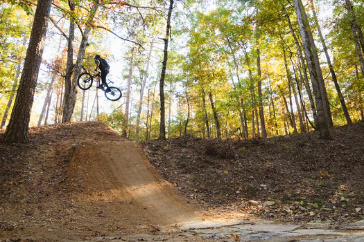 Mountain biker in air after high jump from dirt single track in Northwoods, Arkansas. 