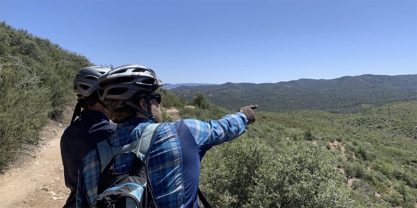 Mountain bikers standing on trail, pointing off into the distance near Prescott, AZ. 