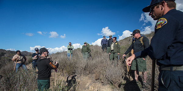 Trail builders standing around leaning on tools, talking singletrack trail development.